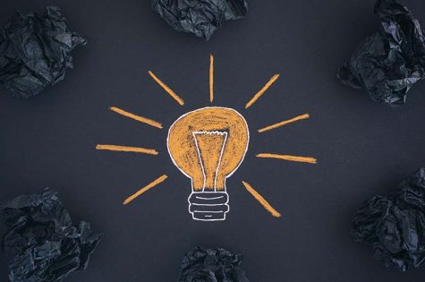 New Idea Concept. Drawing of a light bulb and black crumpled paper balls.